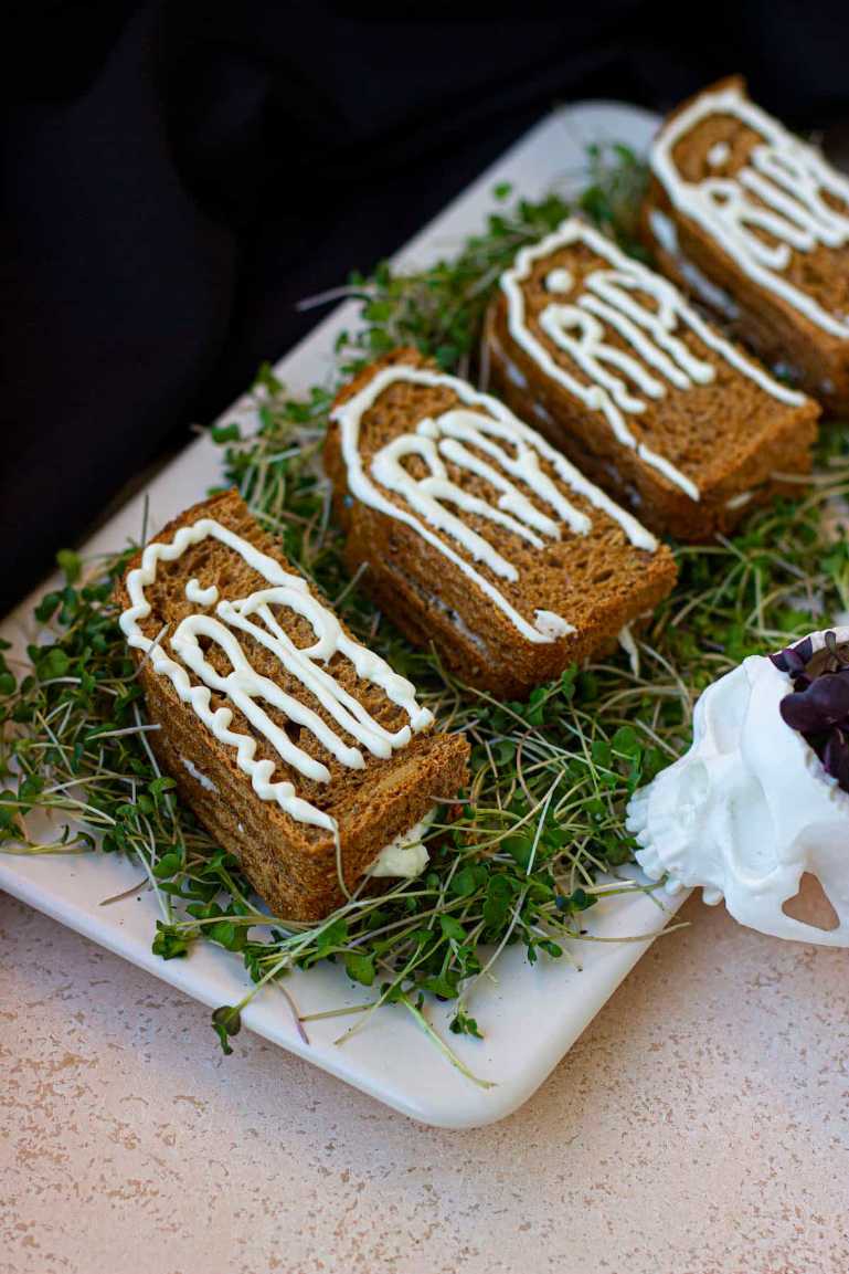 Mini turkey and cheese sandwiches cut into pumpkin shapes, with olive “stems” on a festive plate